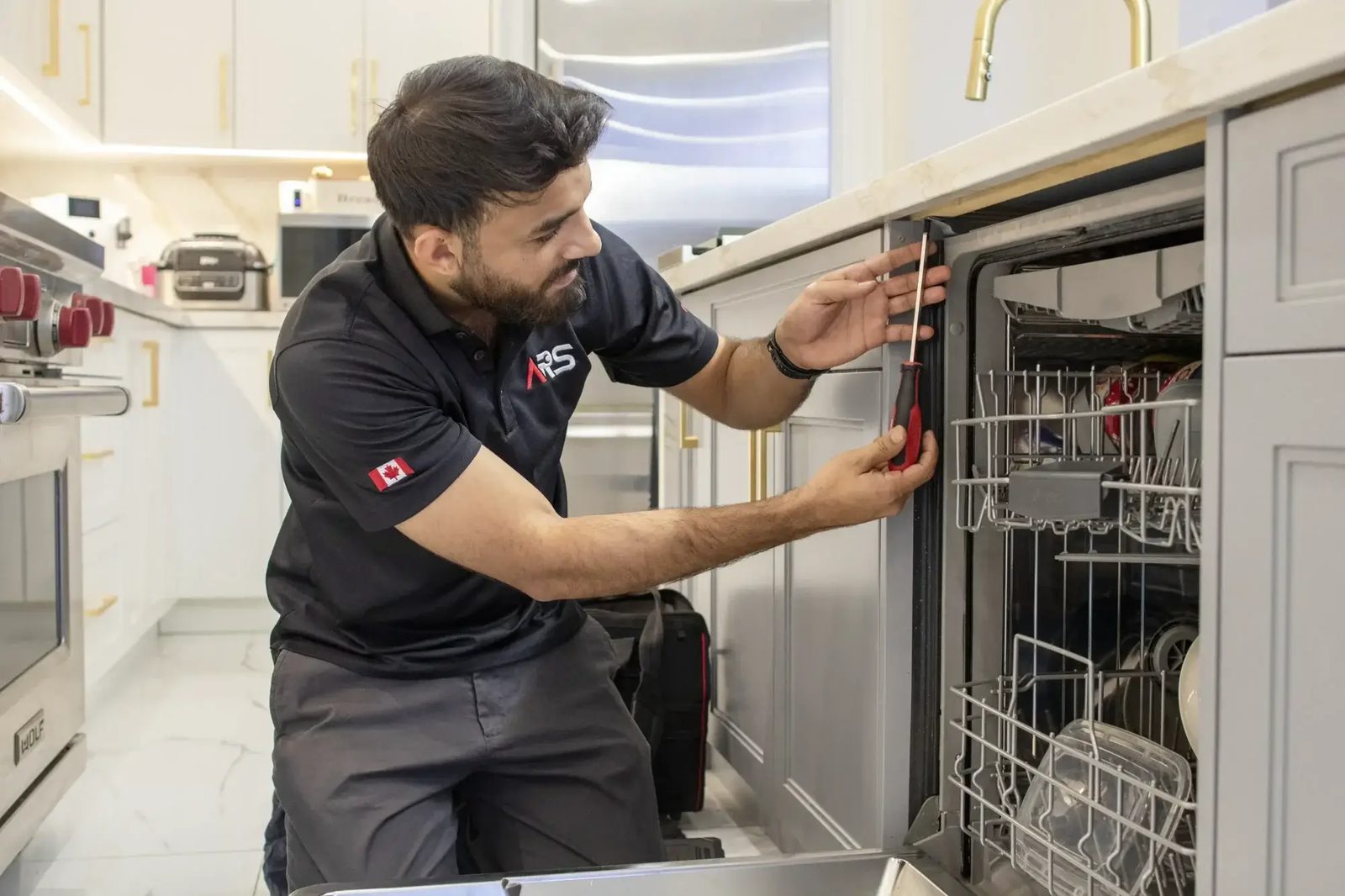Technician repairing a built in dishwasher with the door open
